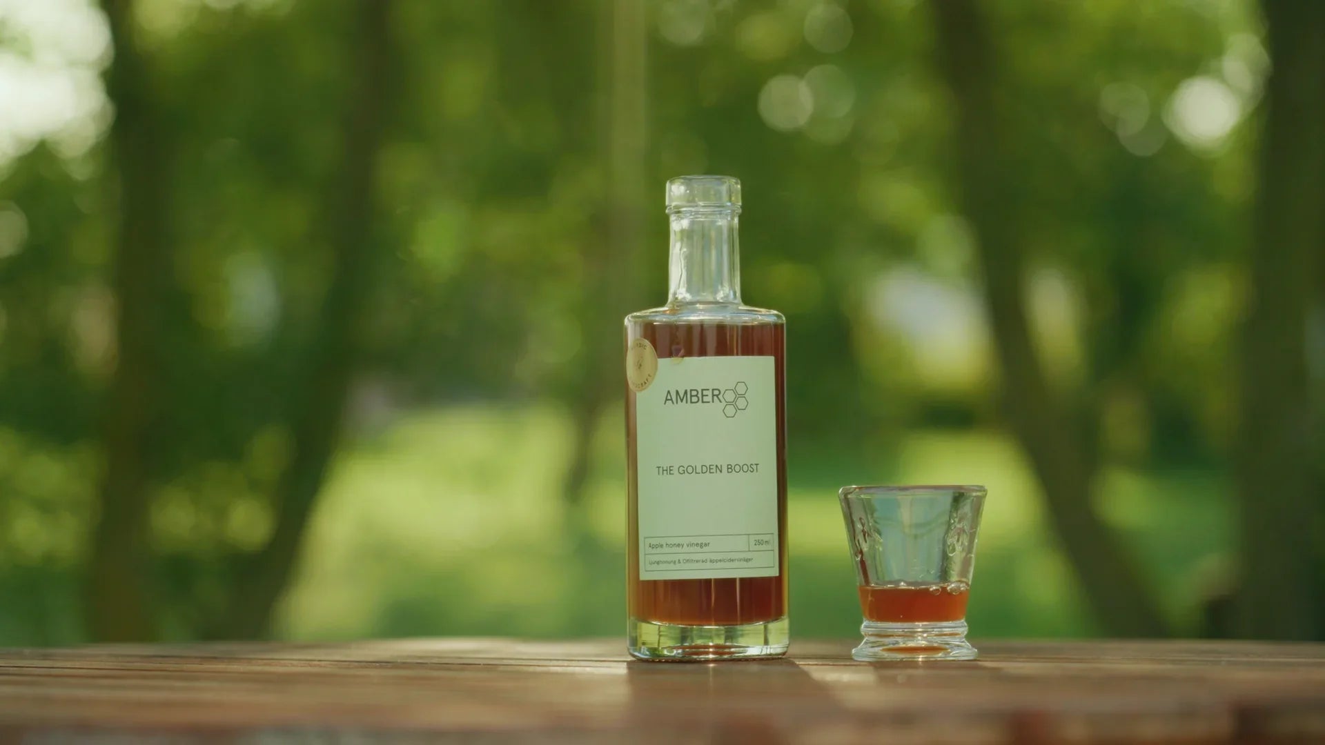 Flaska med äppelcidervinäger med honung och ett glas, naturlig utomhusmiljö, ekologisk honungsvinäger